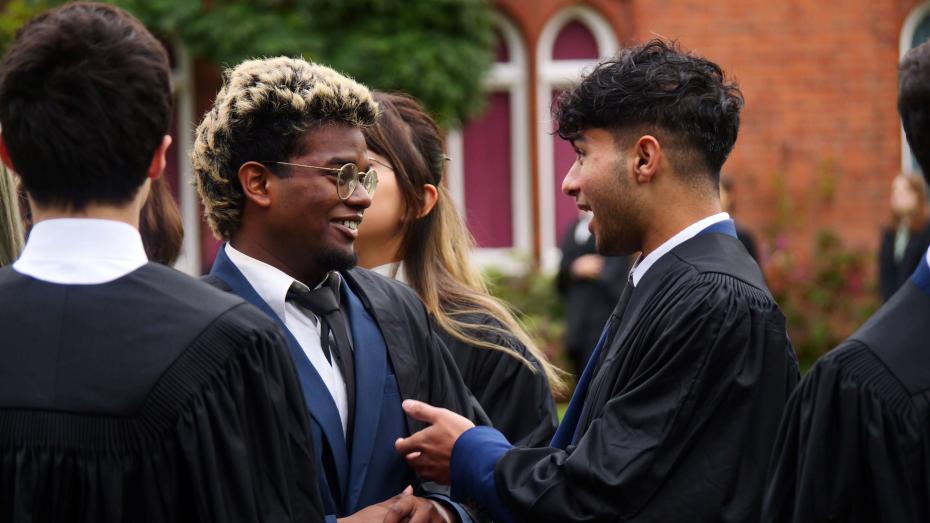 two students in gowns talking to eachother